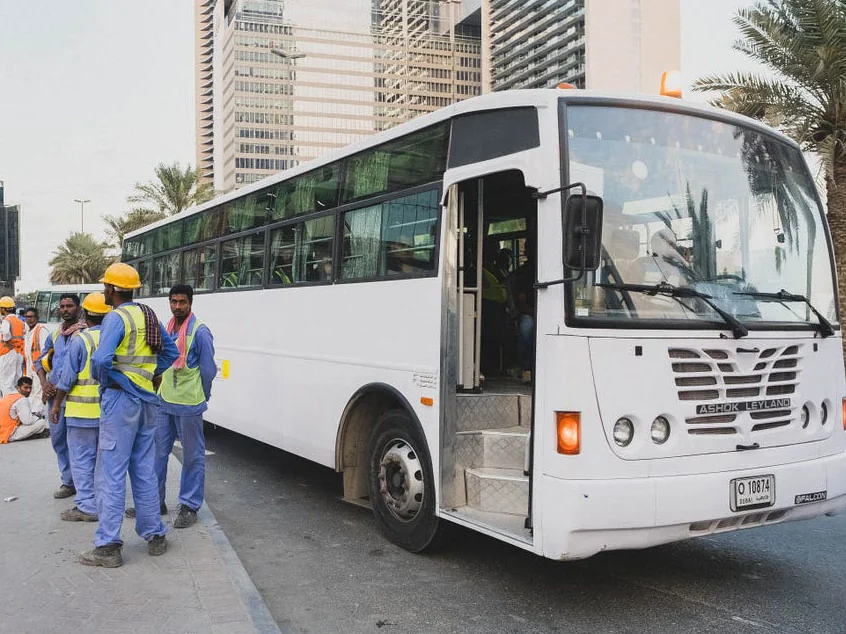 Workers boarding a company bus for site rotation in Doha