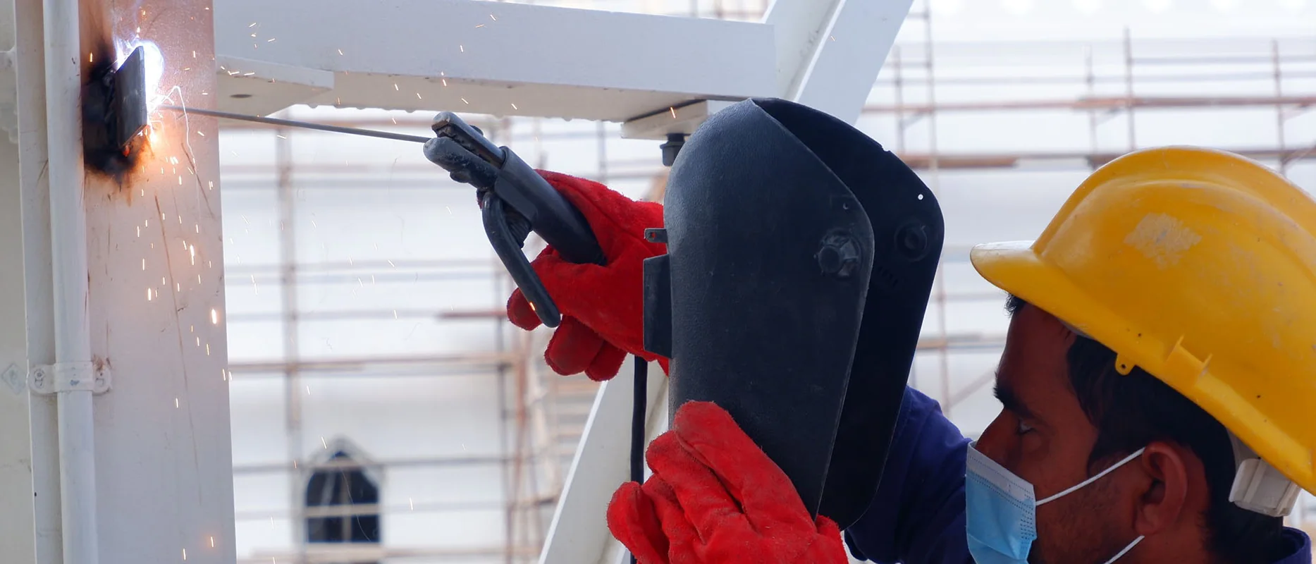 Welders in helmets, gloves and eye protection at work