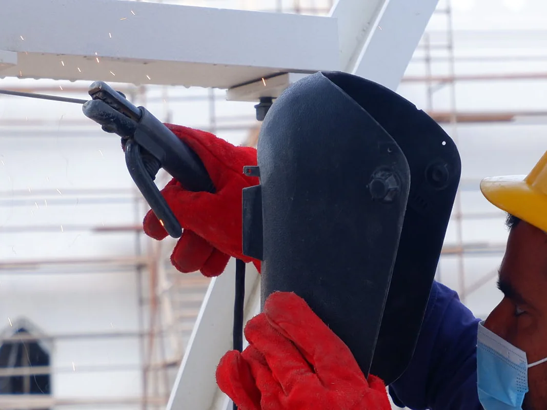 Welders wearing helmets, gloves and eye protection on site