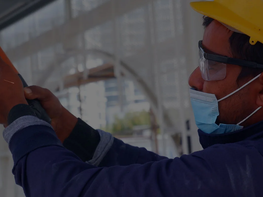 Skilled worker using an angle grinder with full protective equipment